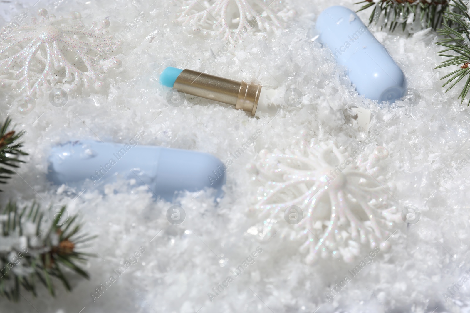 Moisturizing lip balms, Christmas decor and fir tree branches on artificial snow, closeup. Winter care Photo of Moisturizing lip balms, Christmas decor and fir tree branches on artificial snow, closeup. Winter care
