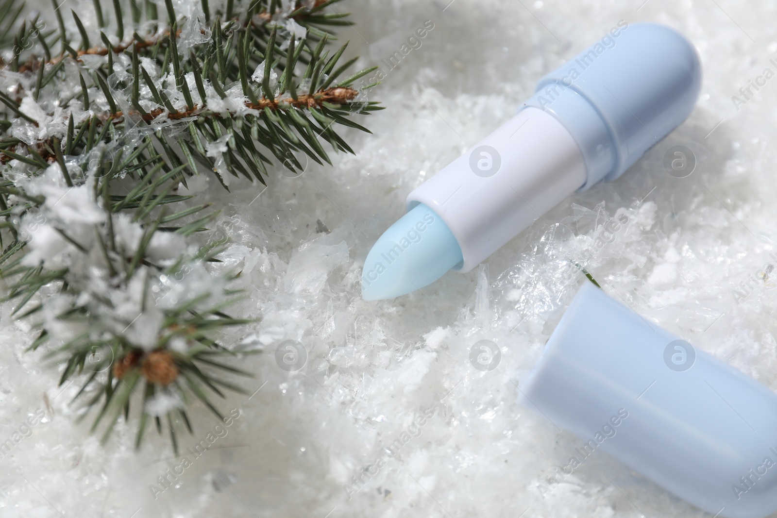 Moisturizing lip balm and fir tree branches on artificial snow, closeup. Winter care Photo of Moisturizing lip balm and fir tree branches on artificial snow, closeup. Winter care