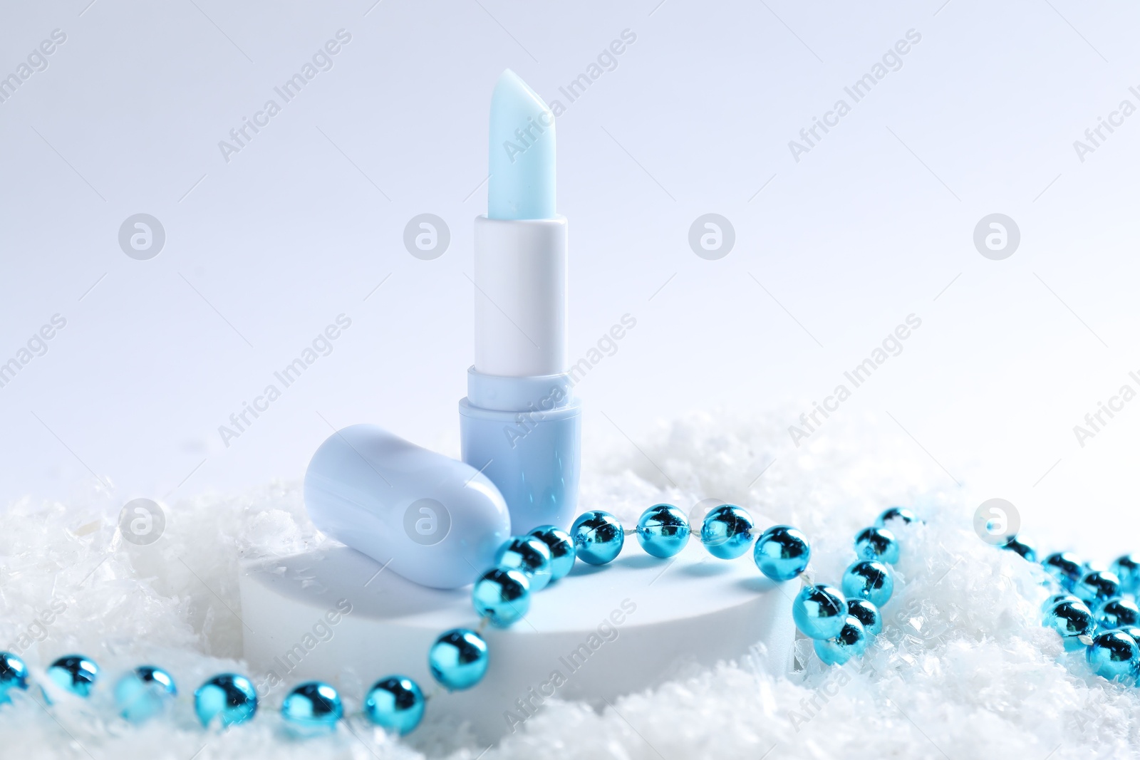 Moisturizing lip balm and Christmas decor on artificial snow, closeup. Winter care Photo of Moisturizing lip balm and Christmas decor on artificial snow, closeup. Winter care