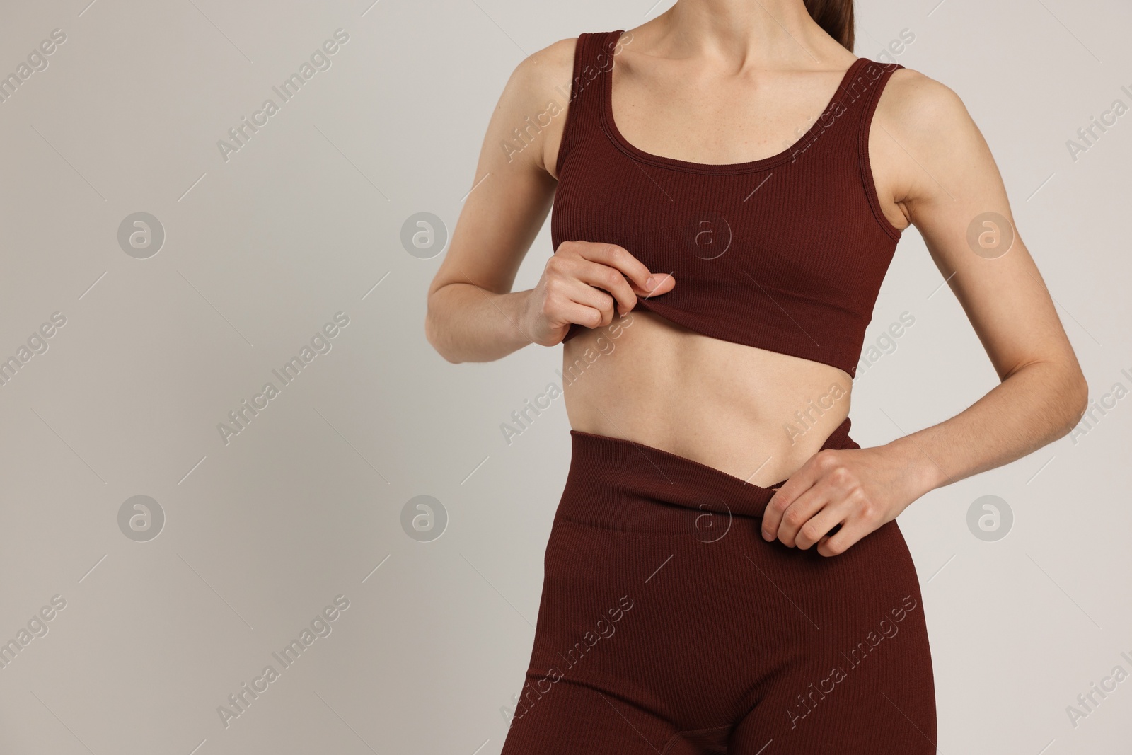 Photo of Woman with flat belly on gray background closeup. Space for text