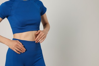 Photo of Woman with flat belly on gray background closeup. Space for text