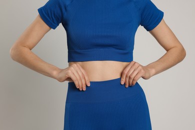 Photo of Woman with flat belly on gray background closeup