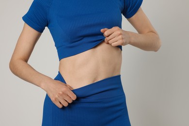 Photo of Woman with flat belly on gray background closeup