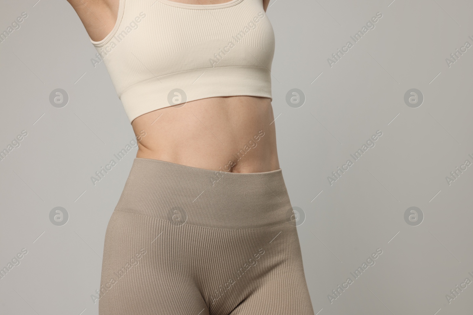 Beautiful woman with flat belly on gray background, closeup Photo of Beautiful woman with flat belly on gray background, closeup