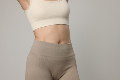 Photo of Beautiful woman with flat belly on gray background, closeup