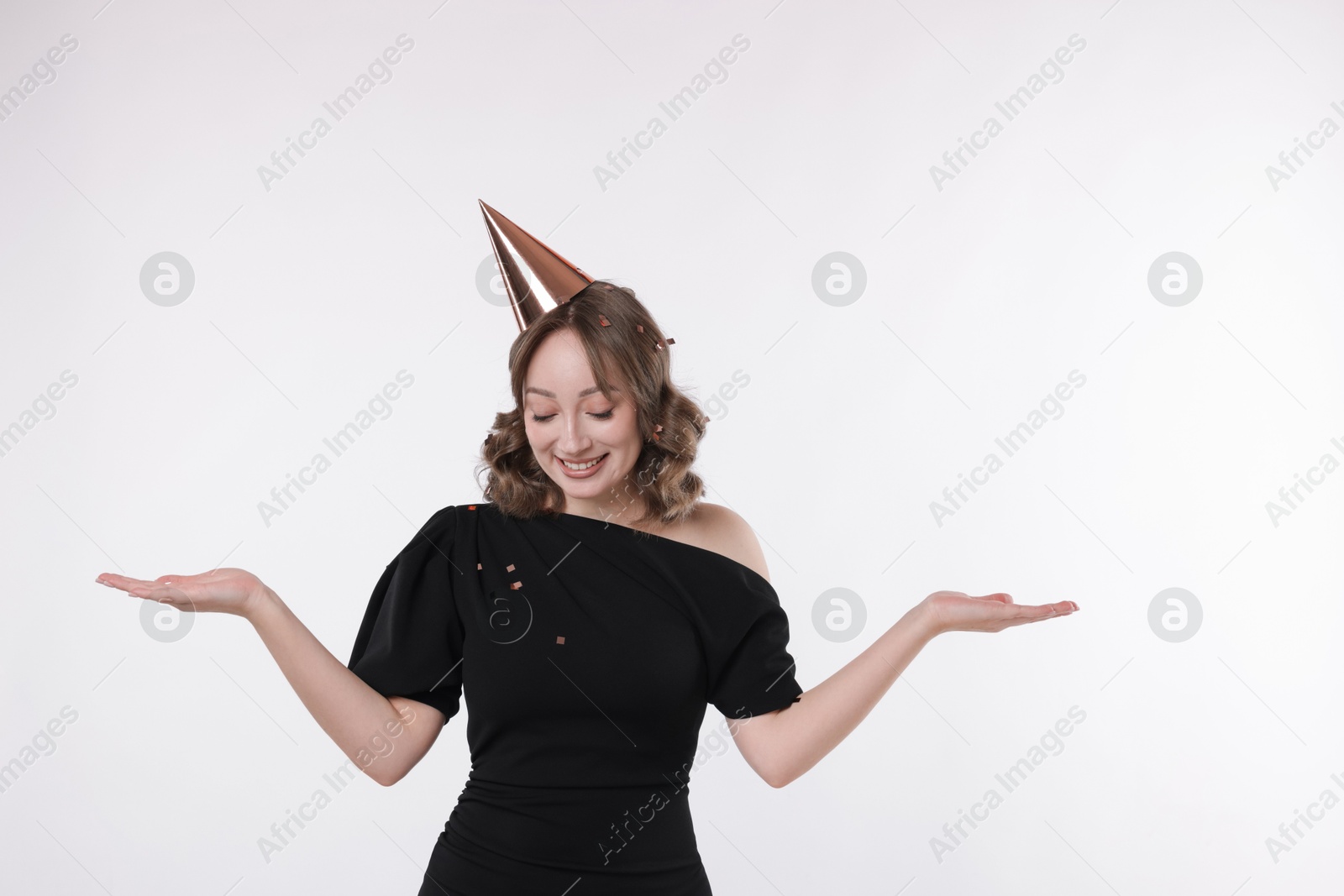 Photo of Birthday celebration. Woman with party cone and confetti on white background. Space for text