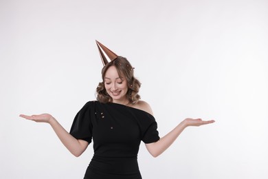 Photo of Birthday celebration. Woman with party cone and confetti on white background. Space for text