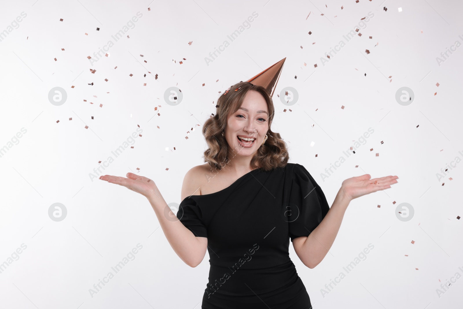 Photo of Birthday celebration. Woman with party cone and confetti on white background