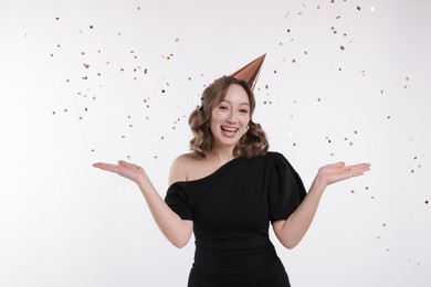 Photo of Birthday celebration. Woman with party cone and confetti on white background