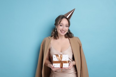 Photo of Birthday celebration. Woman with gift on light blue background