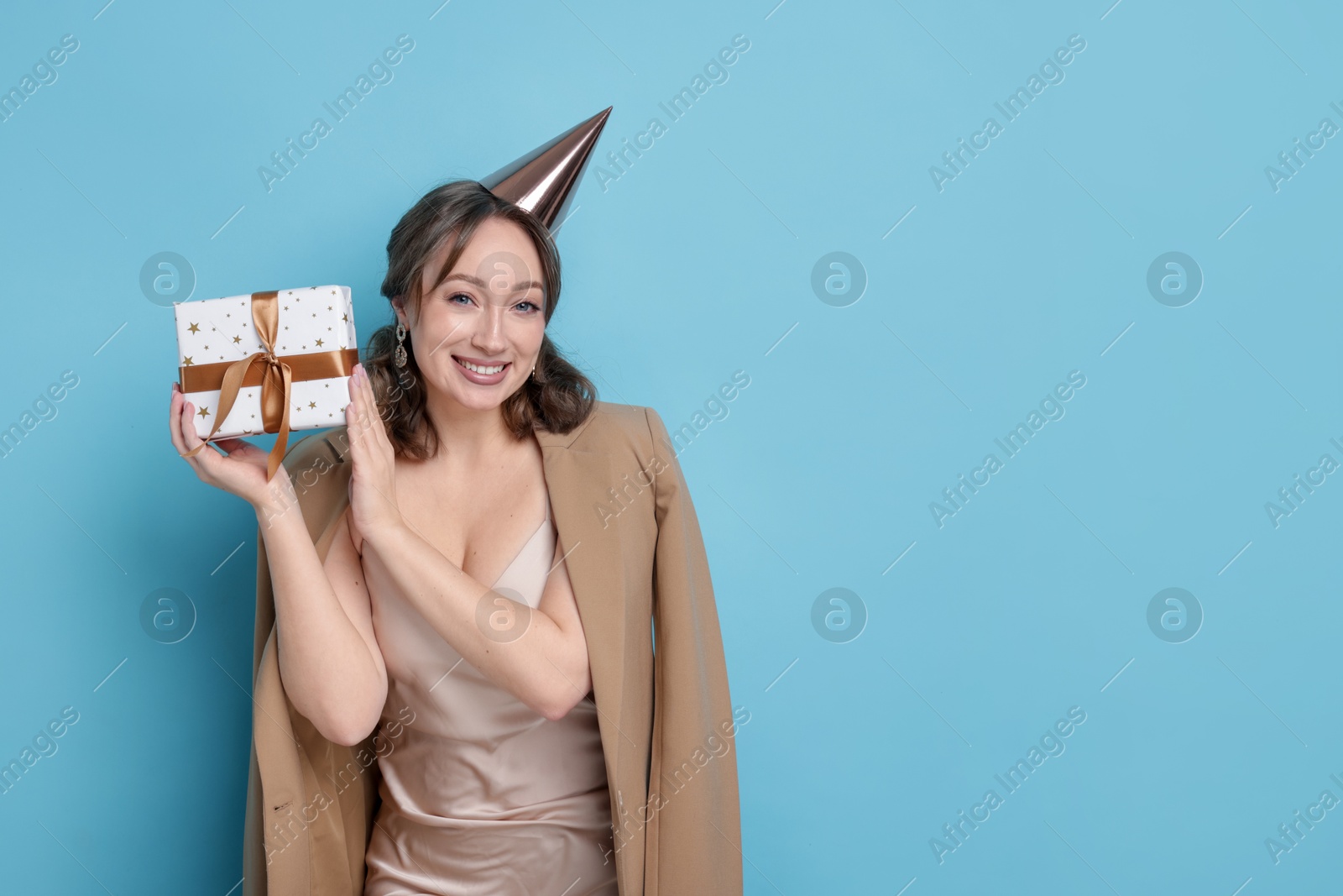 Birthday celebration. Woman with gift on light blue background. Space for text Photo of Birthday celebration. Woman with gift on light blue background. Space for text