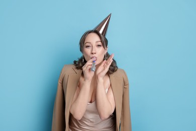 Photo of Birthday celebration. Woman with party horn on light blue background