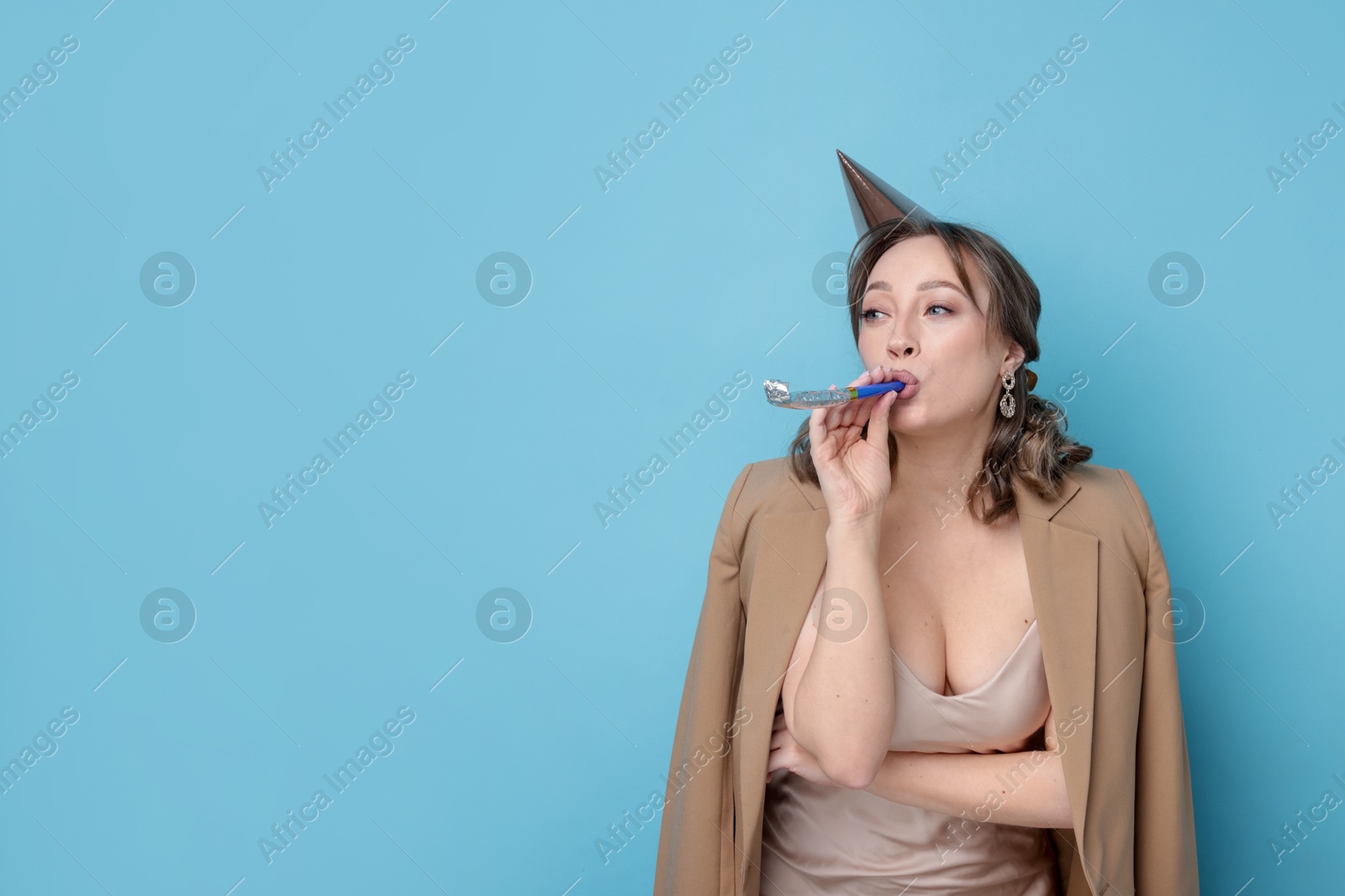 Photo of Birthday celebration. Woman with party horn on light blue background. Space for text