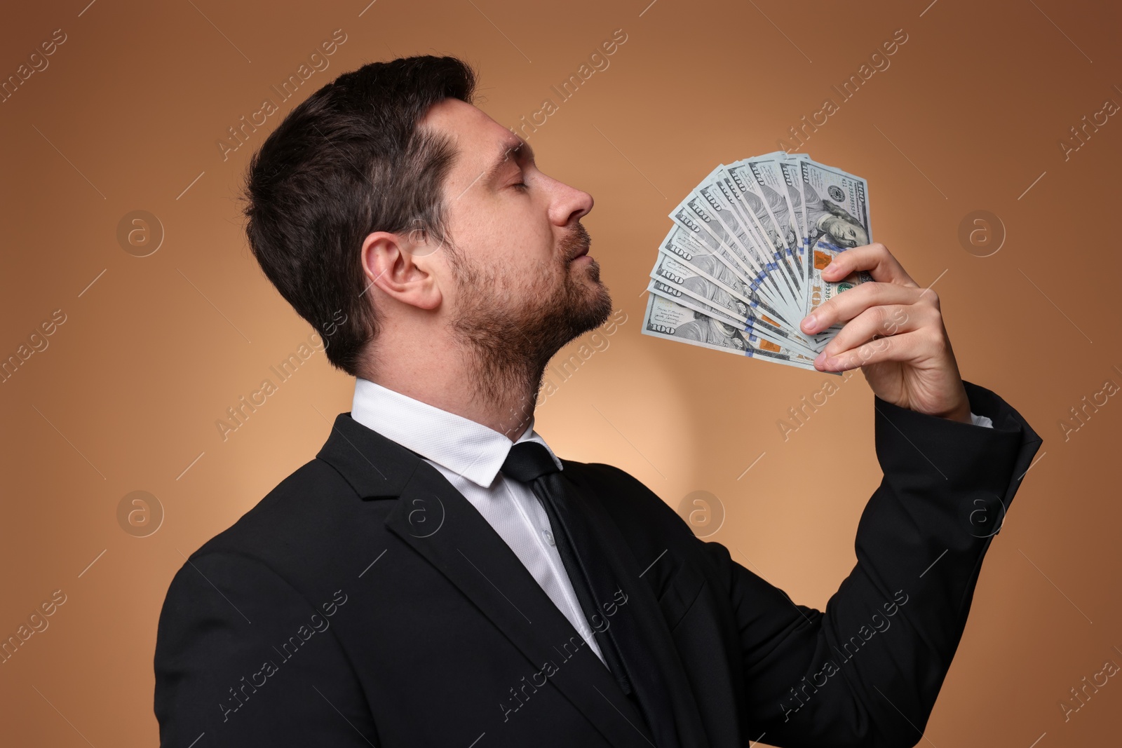 Greedy banker with dollar banknotes on golden background Photo of Greedy banker with dollar banknotes on golden background