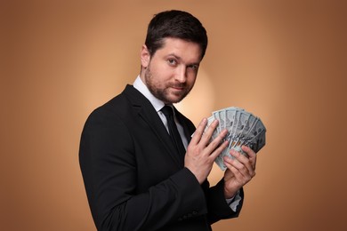 Photo of Greedy banker with dollar banknotes on golden background