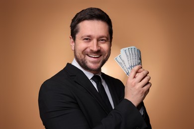 Photo of Happy greedy banker with dollar banknotes on golden background