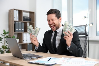 Photo of Happy greedy banker with dollar banknotes at table in office