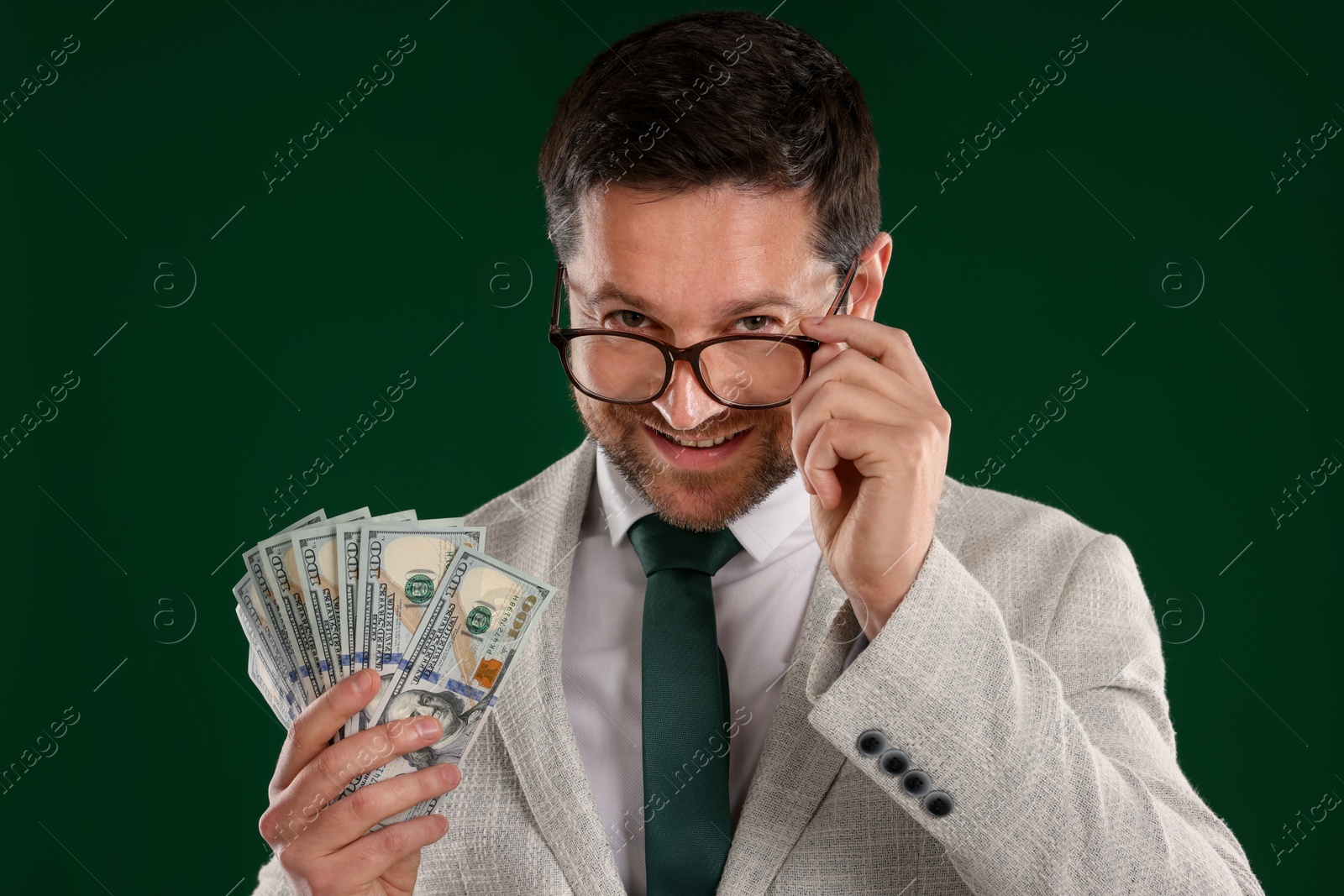 Happy greedy banker with dollar banknotes on green background Photo of Happy greedy banker with dollar banknotes on green background