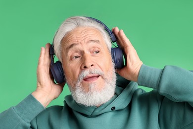 Photo of Elderly man in headphones on green background