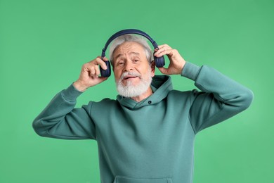 Photo of Elderly man in headphones on green background