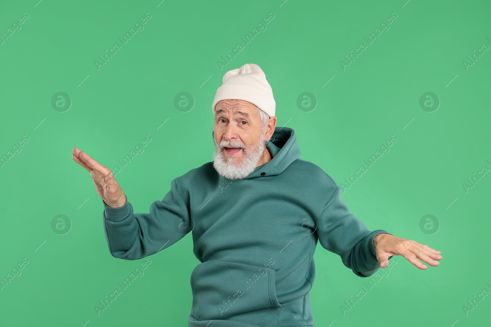 Elderly man in stylish outfit on green background Photo of Elderly man in stylish outfit on green background