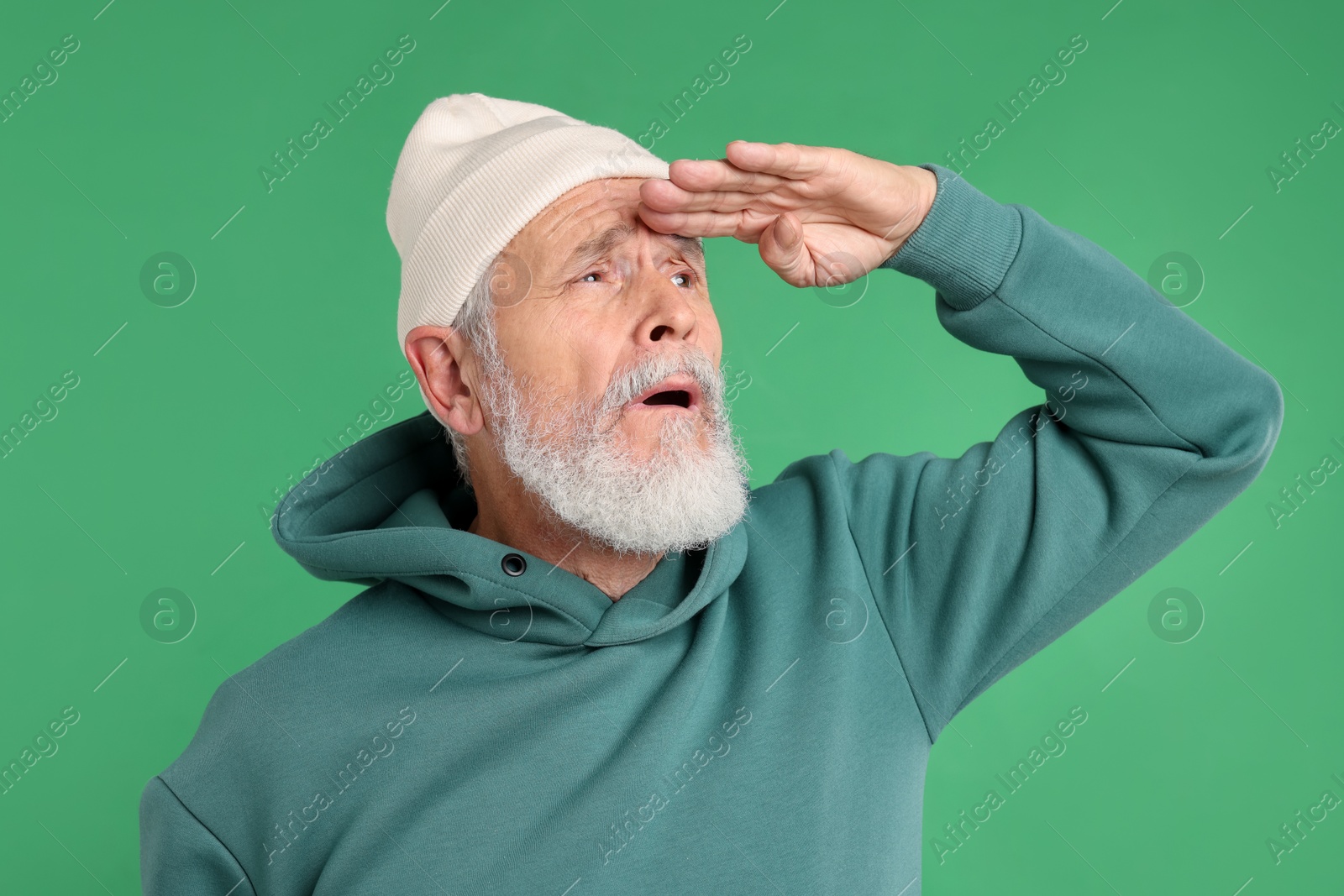 Elderly man in stylish outfit on green background Photo of Elderly man in stylish outfit on green background