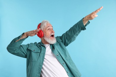 Photo of Elderly man in headphones on light blue background