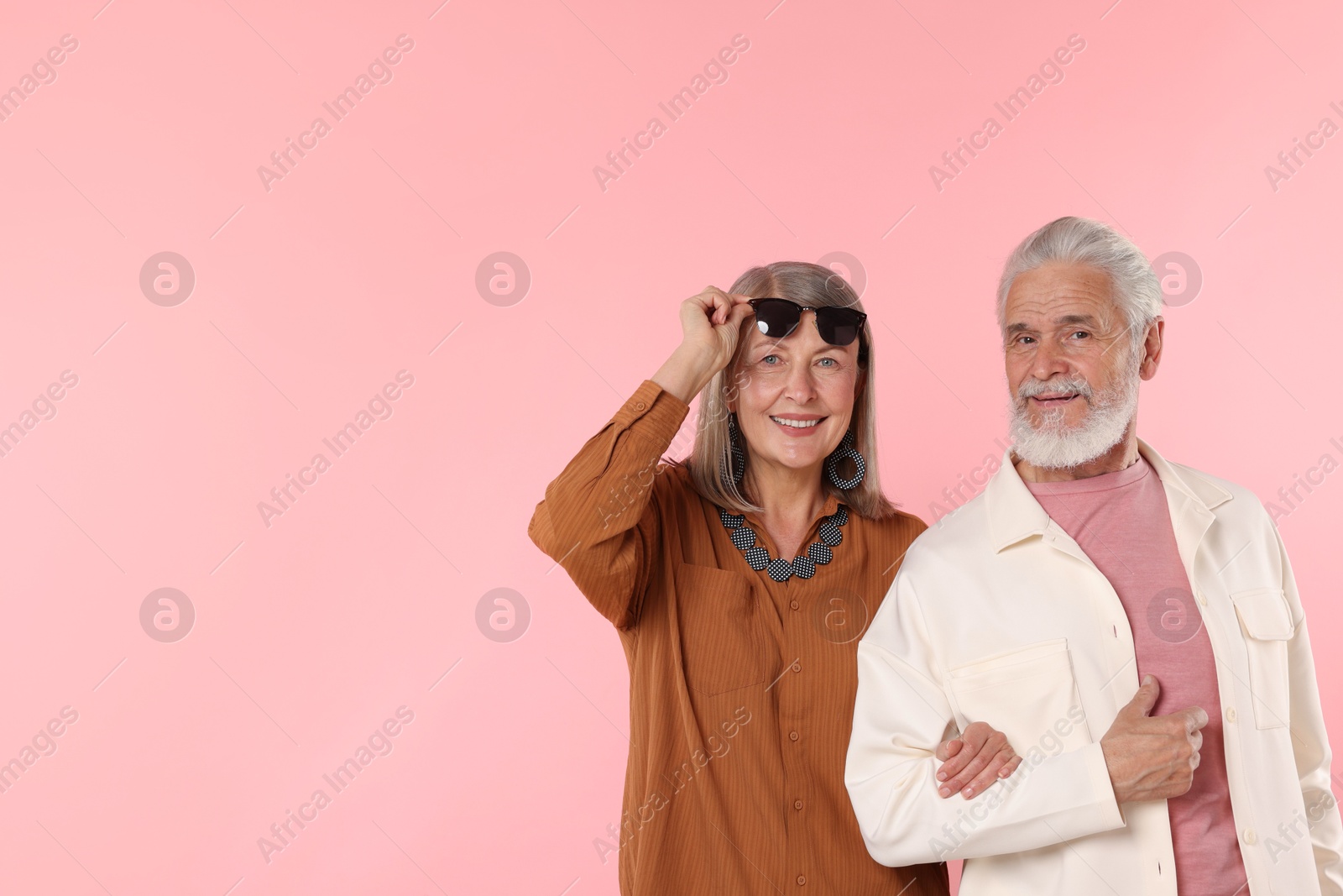 Senior couple in stylish outfits on pink background, space for text Photo of Senior couple in stylish outfits on pink background, space for text