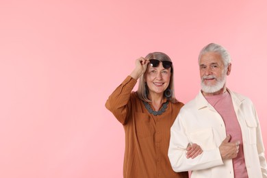 Photo of Senior couple in stylish outfits on pink background, space for text