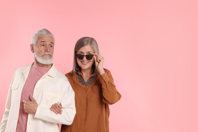 Photo of Senior couple in stylish outfits on pink background, space for text