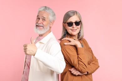 Photo of Senior couple in stylish outfits on pink background