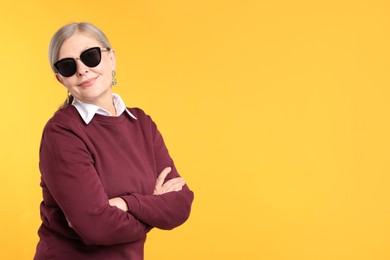 Photo of Senior woman in stylish outfit on orange background, space for text