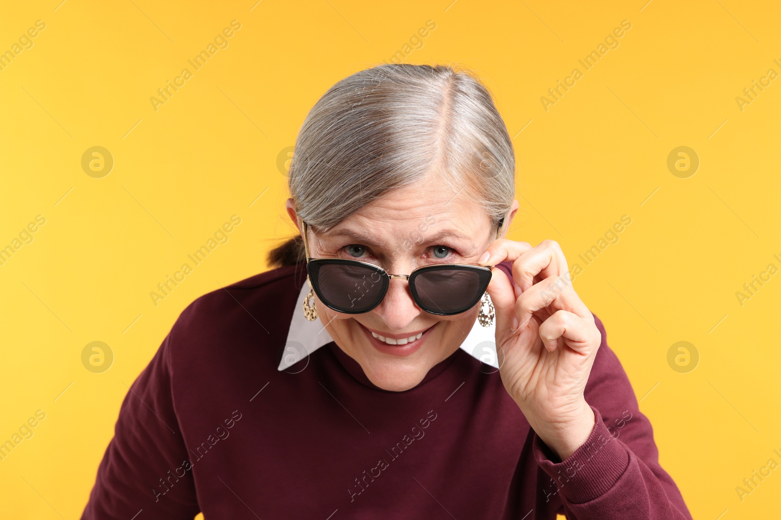 Photo of Happy senior woman in stylish outfit on orange background