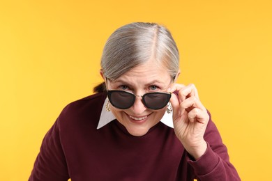 Photo of Happy senior woman in stylish outfit on orange background