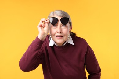 Photo of Senior woman in stylish outfit on orange background