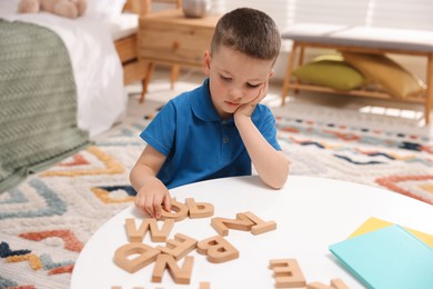 Photo of Dyslexia. Little boy learning letters at table indoors
