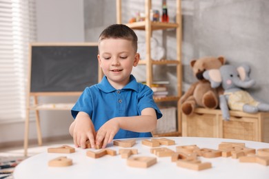 Photo of Dyslexia. Little boy learning letters at table indoors