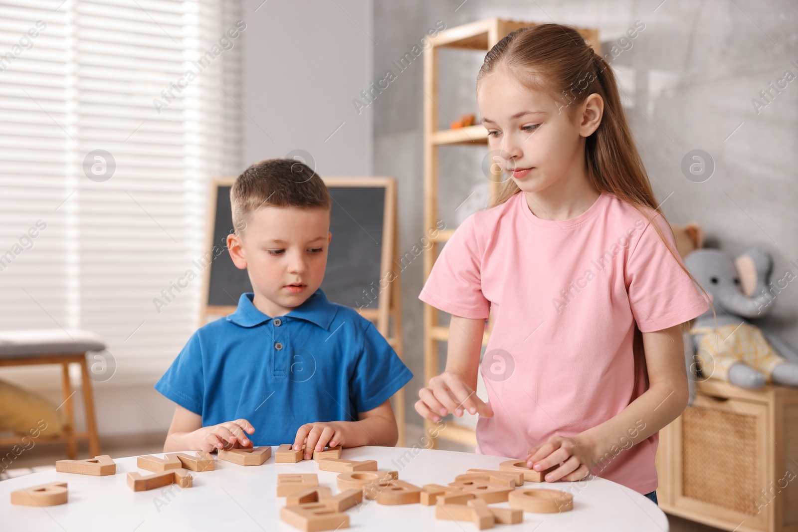 Photo of Dyslexia. Kids learning letters at table indoors