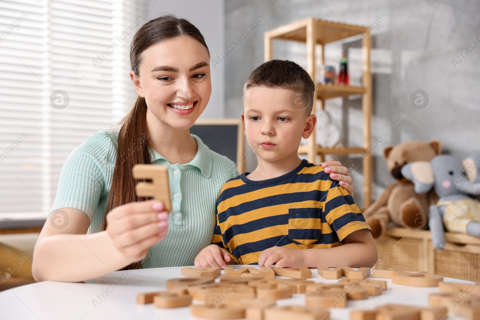 Dyslexia. Mother and her son learning letters at table indoors Photo of Dyslexia. Mother and her son learning letters at table indoors