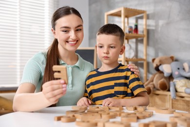 Photo of Dyslexia. Mother and her son learning letters at table indoors