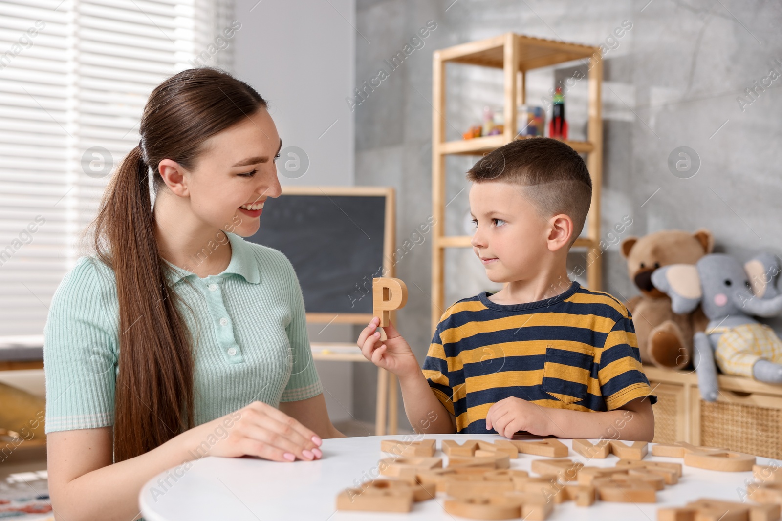 Dyslexia. Mother and her son learning letters at table indoors Photo of Dyslexia. Mother and her son learning letters at table indoors