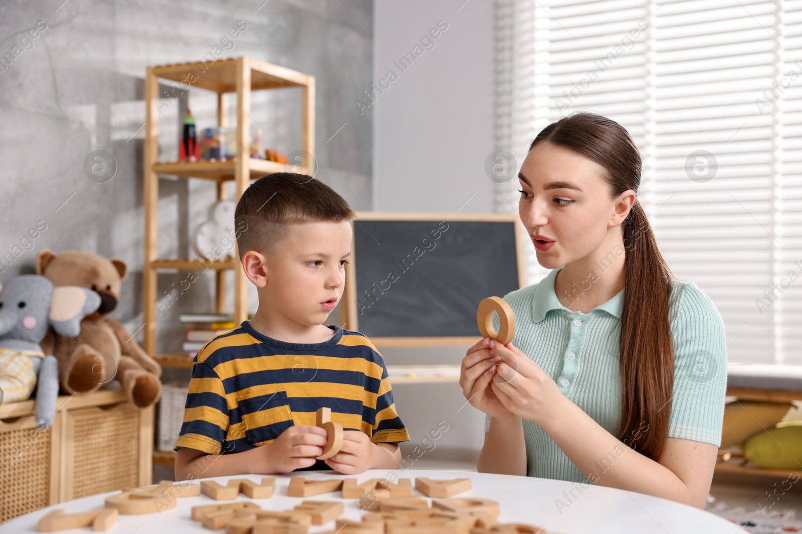 Dyslexia. Mother and her son learning letters at table indoors Photo of Dyslexia. Mother and her son learning letters at table indoors