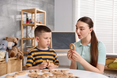 Photo of Dyslexia. Mother and her son learning letters at table indoors