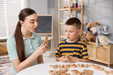 Photo of Dyslexia. Mother and her son learning letters at table indoors