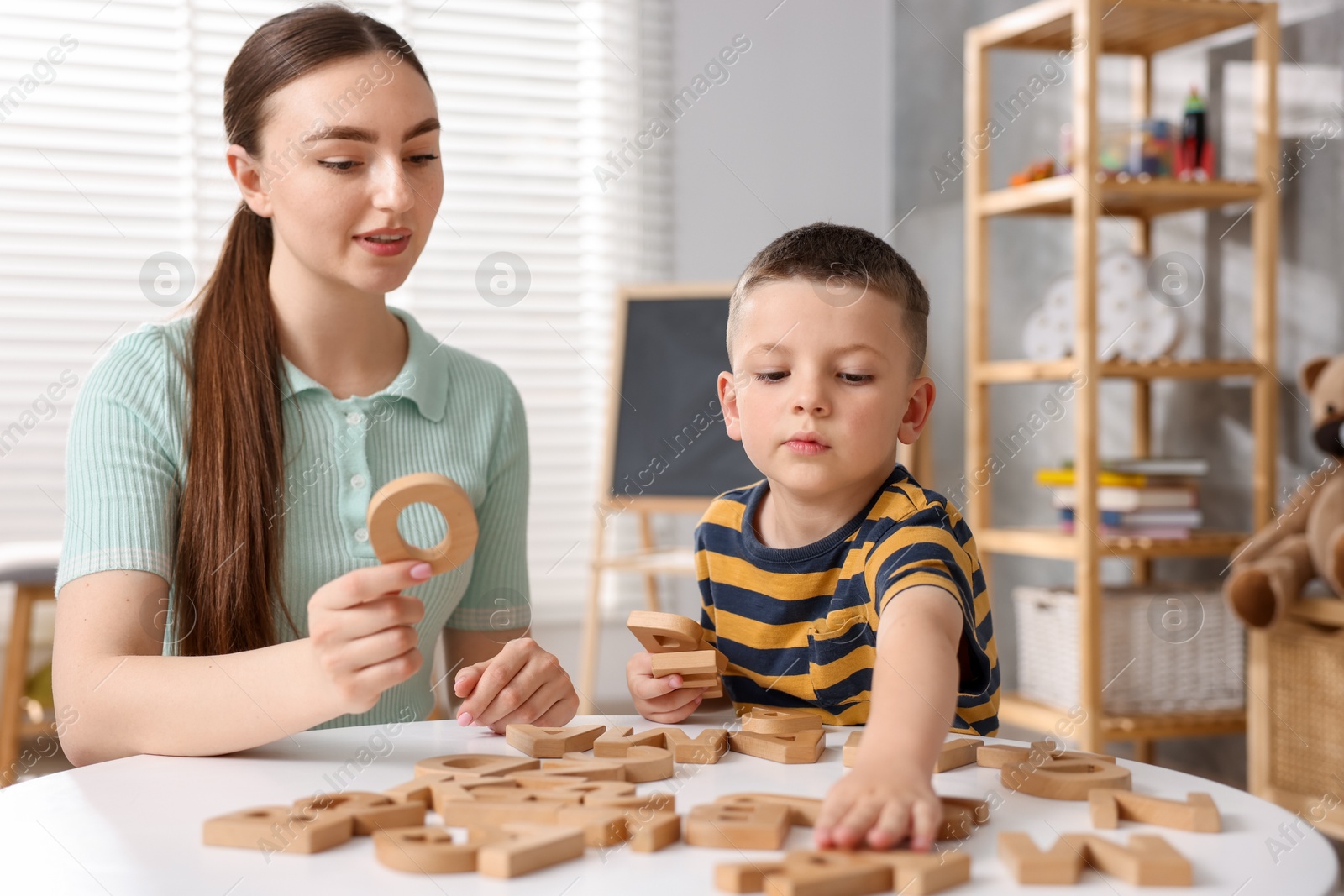 Dyslexia. Mother and her son learning letters at table indoors Photo of Dyslexia. Mother and her son learning letters at table indoors