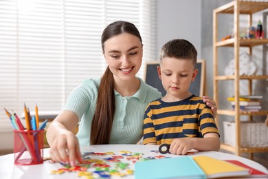 Photo of Dyslexia. Mother and her son learning letters at table indoors