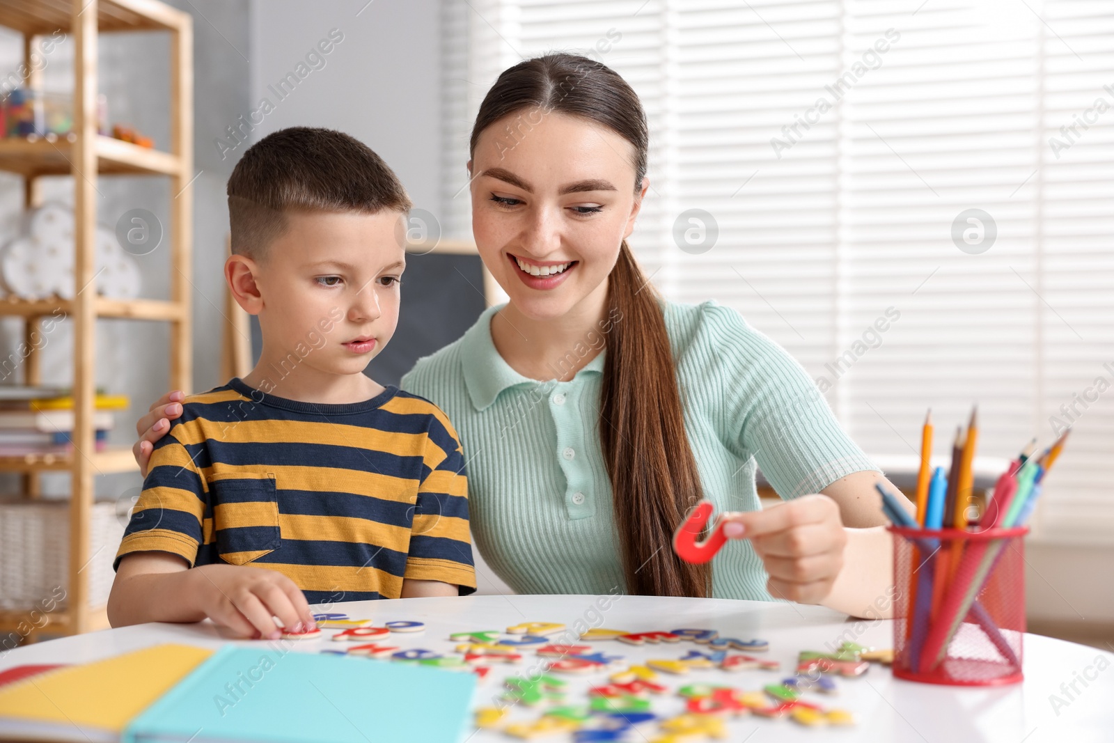 Dyslexia. Mother and her son learning letters at table indoors Photo of Dyslexia. Mother and her son learning letters at table indoors