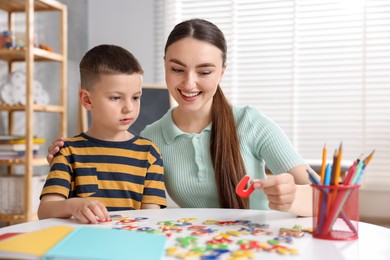 Photo of Dyslexia. Mother and her son learning letters at table indoors
