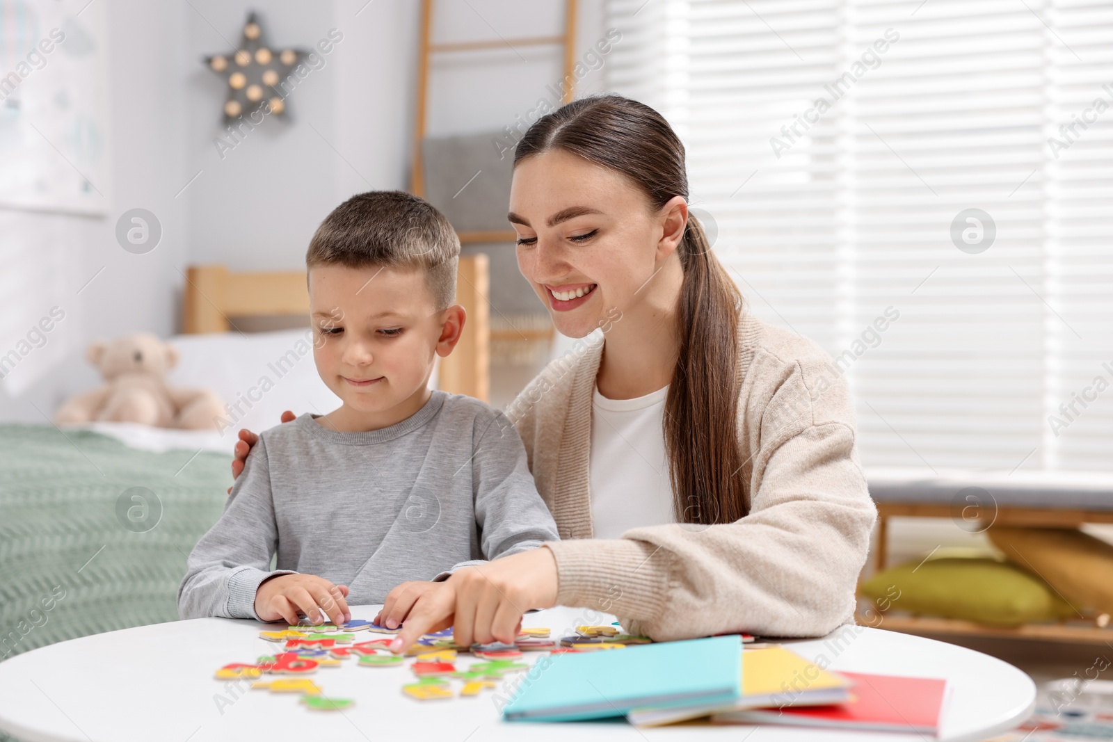 Dyslexia. Mother and her son learning letters at table indoors Photo of Dyslexia. Mother and her son learning letters at table indoors