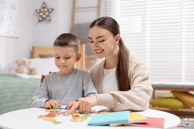 Photo of Dyslexia. Mother and her son learning letters at table indoors
